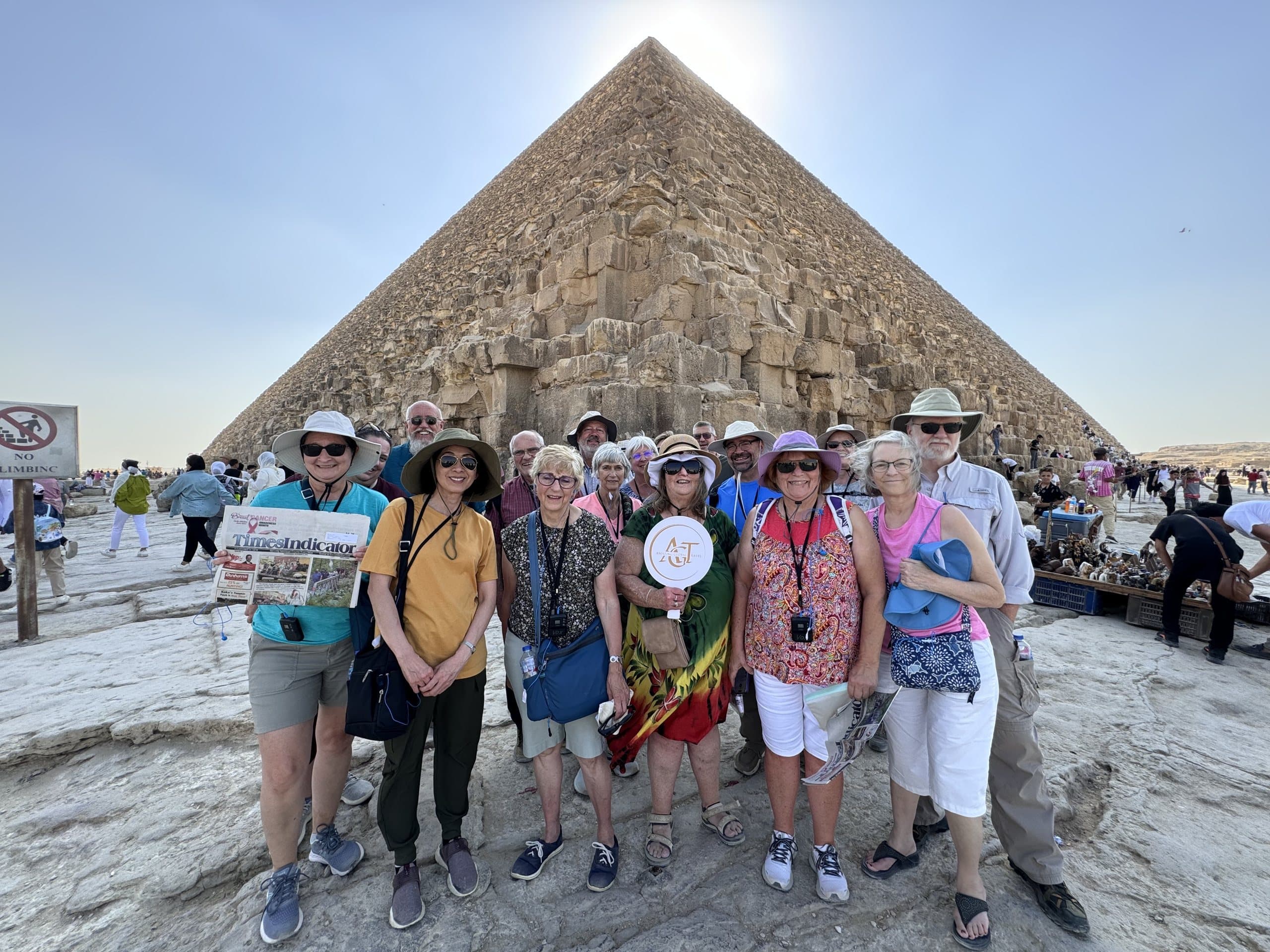 A group of travellers with Amazing Global Travel signs in front of the Great Pyramid of Giza